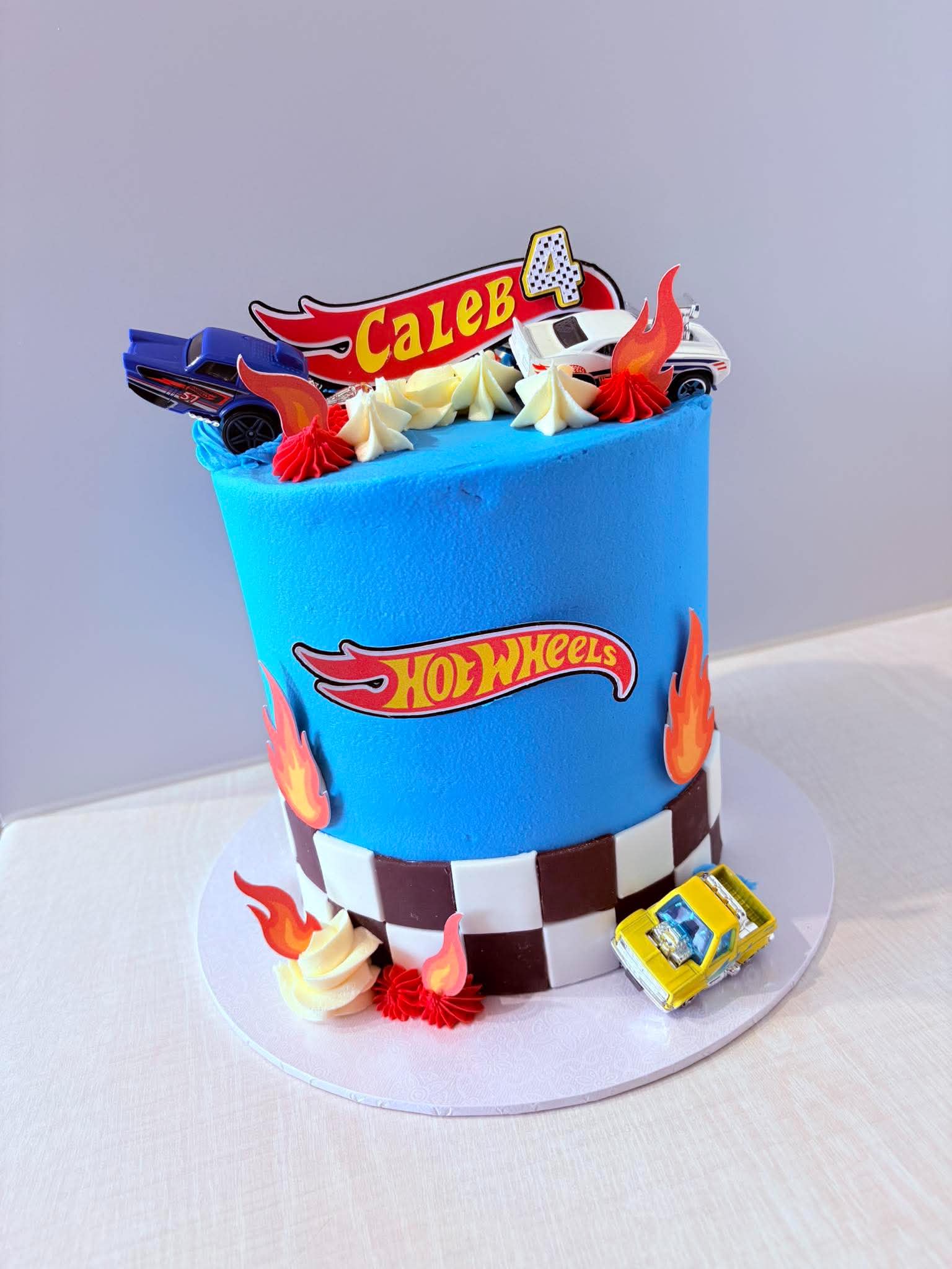 Blue Hot Wheels birthday cake with racing cars and flame decorations