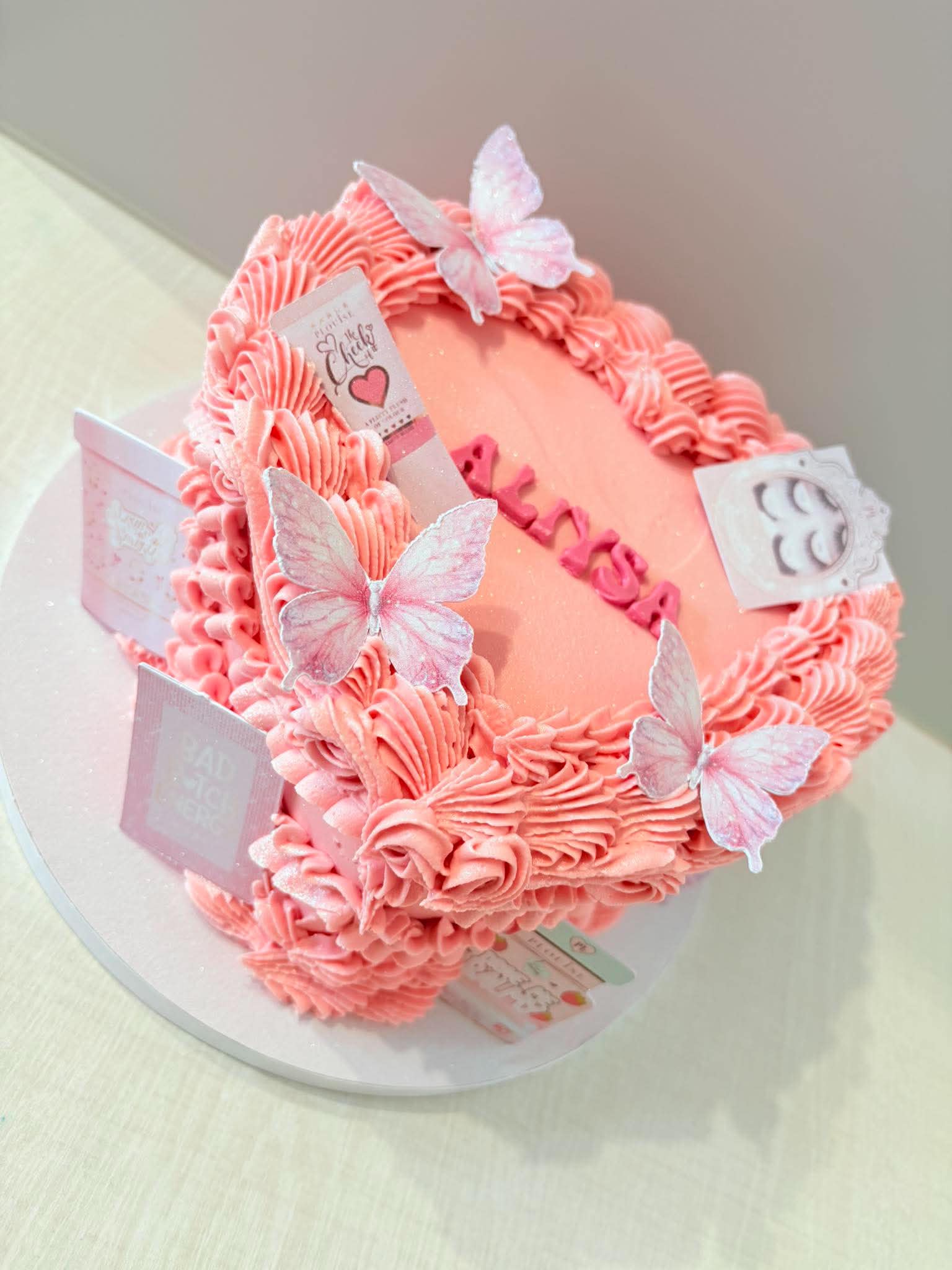 Pink buttercream cake with butterflies, bows and piped ruffles