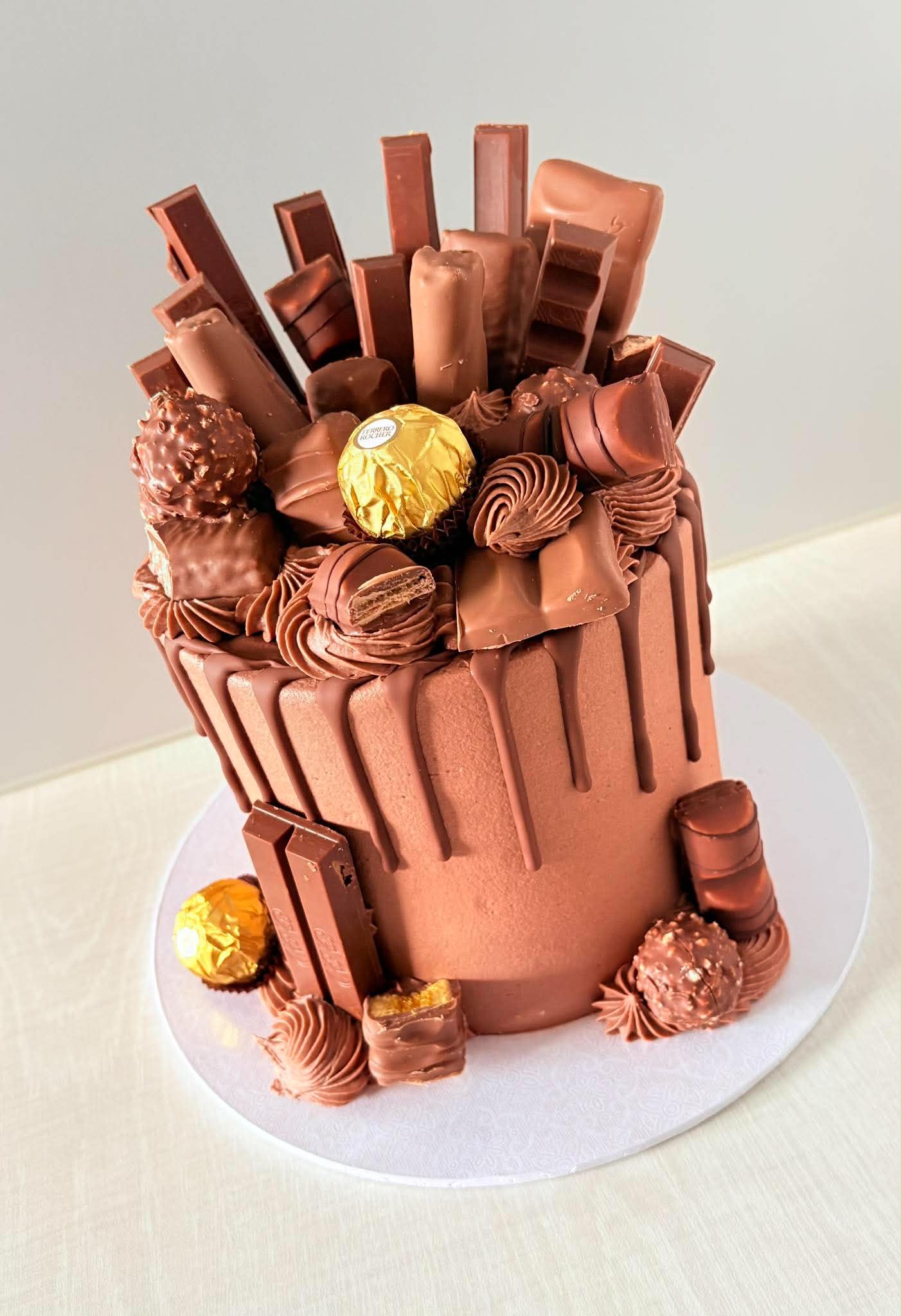 Tall chocolate drip cake piled with chocolate bars and truffles