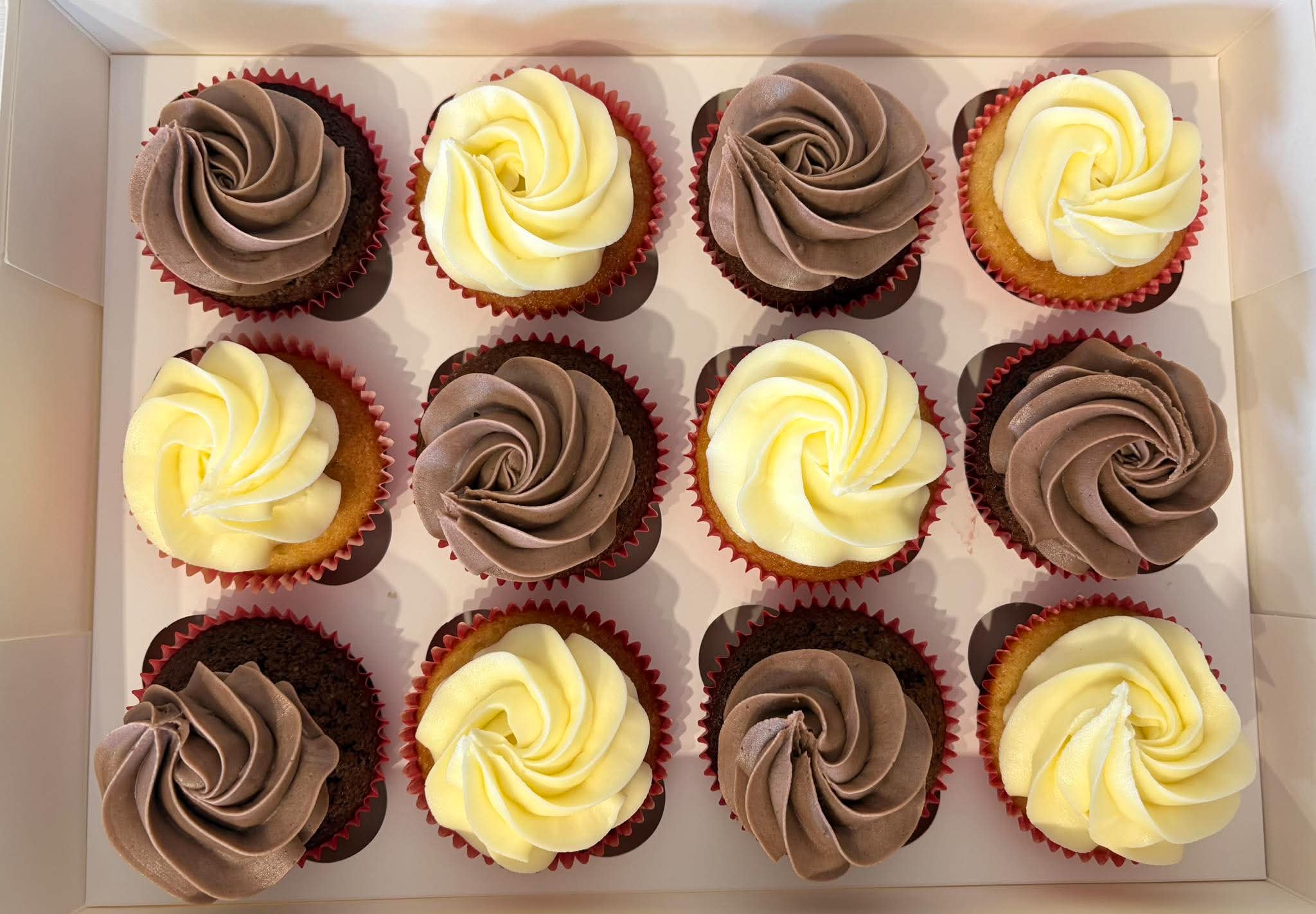 Box of chocolate and vanilla cupcakes topped with buttercream roses