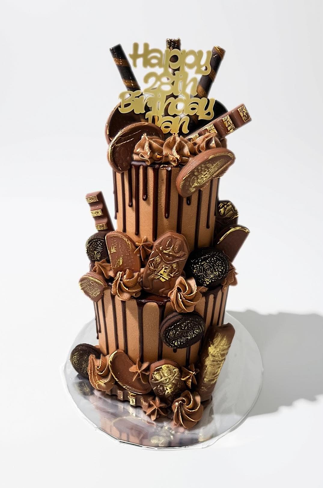 Two-tier chocolate drip cake decorated with chocolates and biscuits