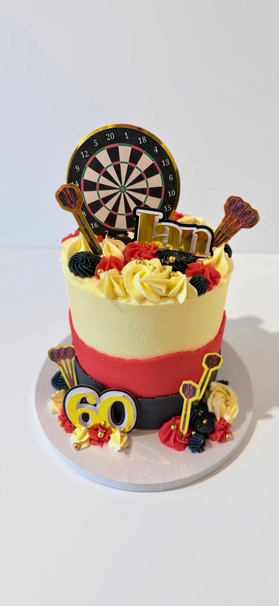 Red, black and ivory cake with a dartboard and darts