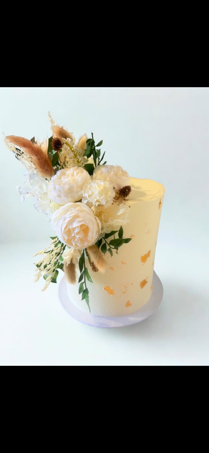 Real ivory wedding cake with white flowers, pampas grass and gold leaf