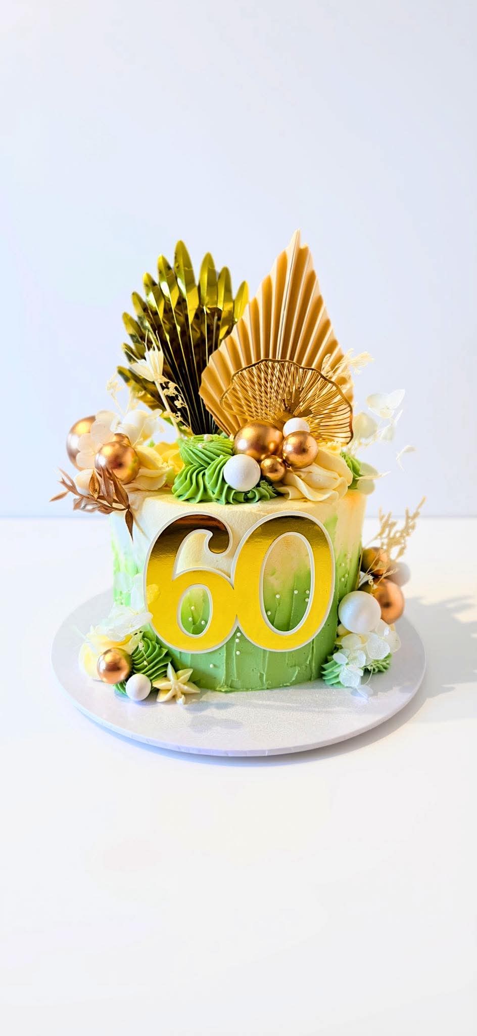Green and ivory celebration cake with gold fans and a 60 topper