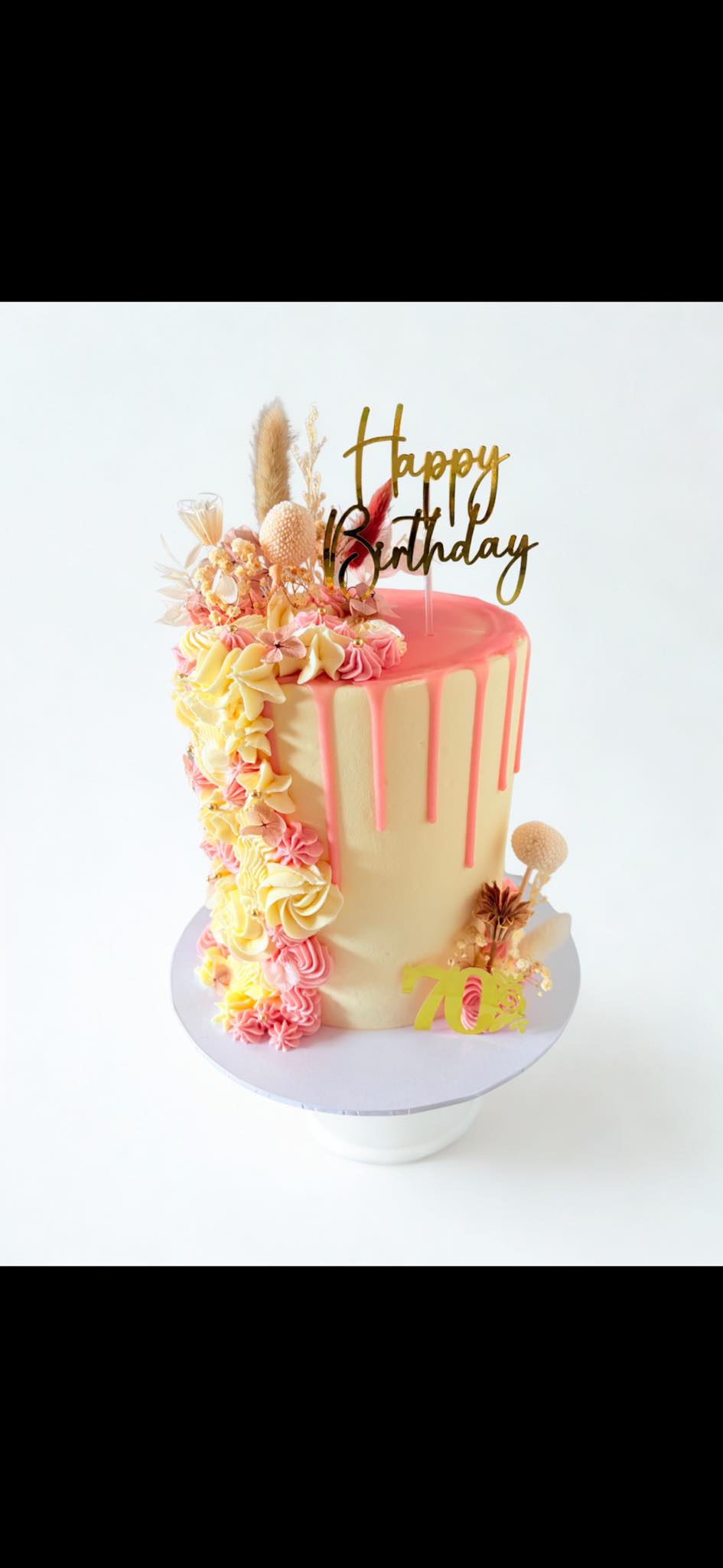 Ivory cake with pink drips, piped flowers and a birthday topper